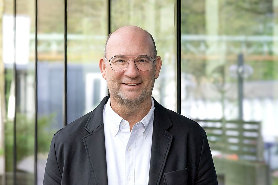 Porträt von Prof. Guido Spars: Mann, lächelnd, mit Brille. Weißes Hemd und schwarze Jacke.