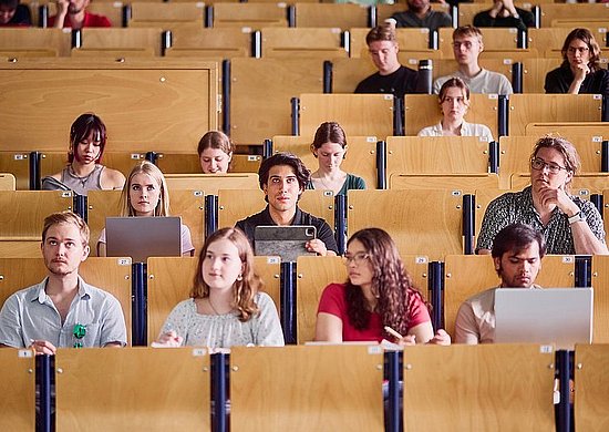 Auf dem Bild sind Student*innen in einem Hörsaal sitzend zu sehen.