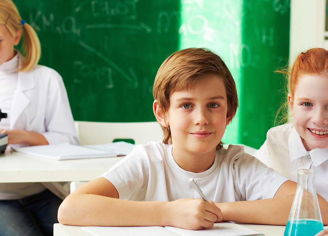 Fröhliche Kinder in einem Klassenzimmer, in dem Unterricht stattfindet.