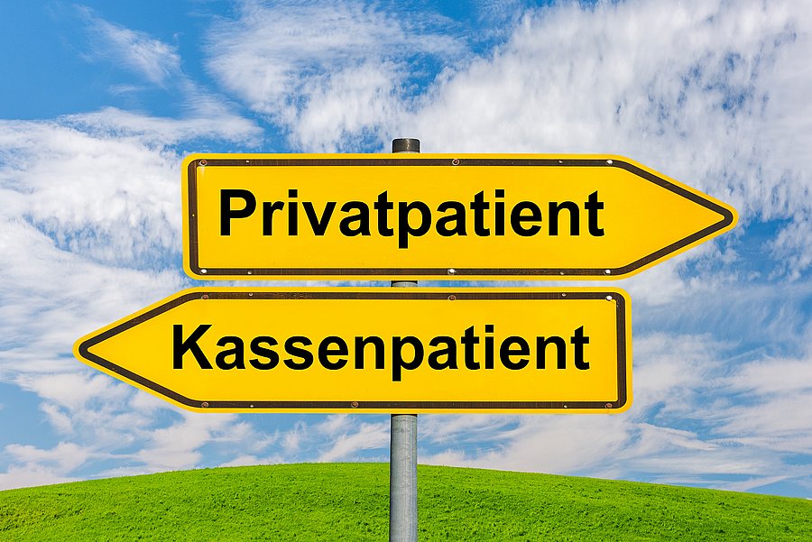 Zwei gelbe Wegweiser vor blauem Himmel: Ein Pfeil weist nach rechts zu „Privatpatient“, der andere nach links zu „Kassenpatient“.