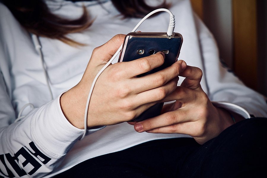 Eine junge Frau bedient ein Smartphone.