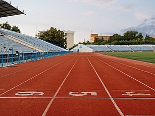 Rennbahn in einem Stadion, mit einem Teil der Tribüne im Bild links 