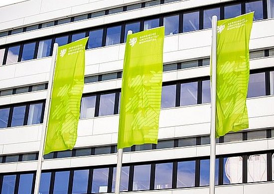 Grüne Fahnen vor einem Uni-Gebäude.