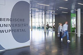 Unigebäude HC mit Bewegungsunschärfe, zwei Studenten gehen durch den Flur